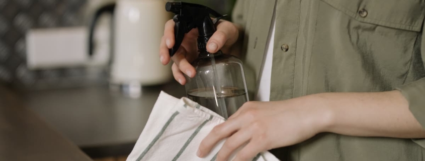 Person cleaning with a spray bottle and cloth, a possible representation of compulsive cleaning behaviors associated with emetophobia and OCD.