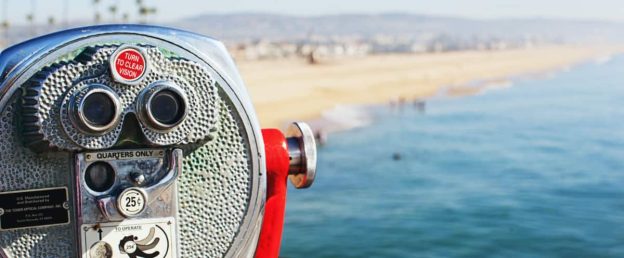 inoculars overlooking a picturesque beach in the distance, symbolizing the importance of seeking professional help for mental health conditions like bipolar disorder treatment in Newport Beach