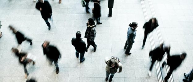 Image of a person standing still in a crowded space while others are walking past, representing social isolation and the effects of Avoidant Personality Disorder (AvPD).