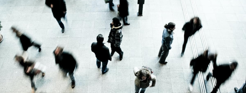 Image of a person standing still in a crowded space while others are walking past, representing social isolation and the effects of Avoidant Personality Disorder (AvPD).