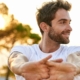 A smiling man with outstretched arms, basking in the sun, symbolizing the uplifting effects of depression treatment in Newport Beach.