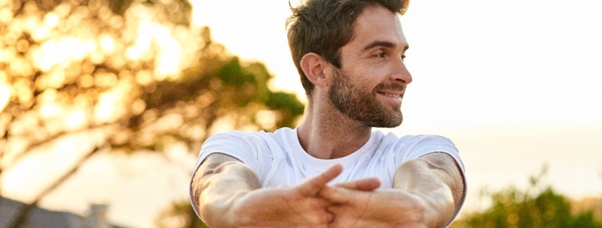 A smiling man with outstretched arms, basking in the sun, symbolizing the uplifting effects of depression treatment in Newport Beach.