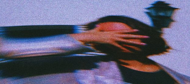 A woman's hand gently covers her face, the image gradually fading into blur, symbolizing the disorientation and confusion often associated with experiencing gaslighting.