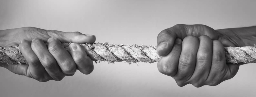 Two hands engaged in a tug-of-war, symbolizing the struggle between mental health and substance abuse.