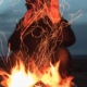 Man shielding his face from intense campfire flames, visually representing signs of anger issues.