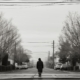 A solitary person walks alone on a quiet suburban street, reflecting the isolating effects of depression.