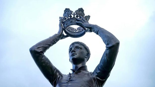 A statue of a man in a contemplative pose, placing a crown atop his own head, symbolizing the concept of grandiose delusions