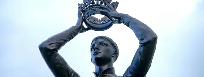 A statue of a man in a contemplative pose, placing a crown atop his own head, symbolizing the concept of grandiose delusions