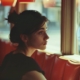 A woman sits alone at a cafe table, gazing out the window reflecting the isolation and introspection associated with depression and eating disorders.