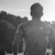 Back view of a man in a t-shirt running on a scenic trail at sunrise, exemplifying how exercise can naturally boost serotonin levels.