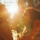 A woman and a man stand together in an urban setting, bathed in sunlight that filters down from behind them, casting a warm glow showing their journey of managing neurotic behavior.