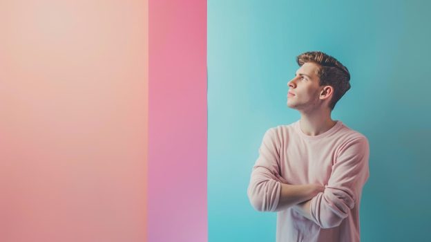 Man against a pastel background with multiple colors looks away deep in thought as though he is showing excessive rumination.