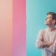 Man against a pastel background with multiple colors looks away deep in thought as though he is showing excessive rumination.