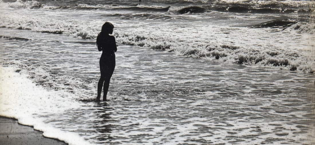 Black and white image of woman at the beach looking at the waves to represent trauma-informed therapy in Newport Beach.