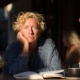 A woman sits quietly at a café with a distant expression, capturing the experience of emotional numbness.