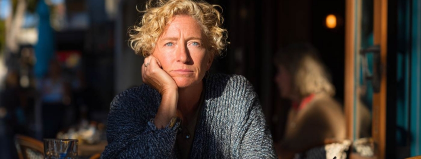 A woman sits quietly at a café with a distant expression, capturing the experience of emotional numbness.
