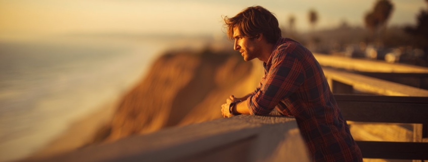 neurodivergent-mental-health-reflection.jpgA young man leans on a railing at sunset, reflecting on neurodivergent mental health.